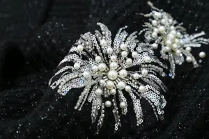 Detailed close-up view of exquisite heavy beaded and sequin embroidery on black knit fabric.