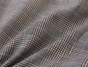 Close-up of classic houndstooth plaid blazer fabric, detailed texture and pattern.