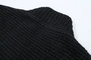 Close-up detail of women's black knitted sweater fabric with shimmering metallic threads.