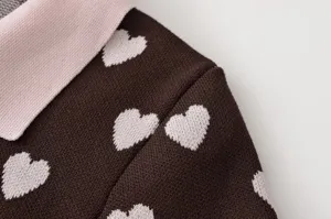 Vue détaillée du haut en tricot pour femme avec motif jacquard cœur rose sur tissu marron.