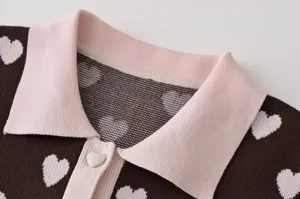 Gros plan détail de polo en tricot jacquard cœur marron pour femme avec col rose.