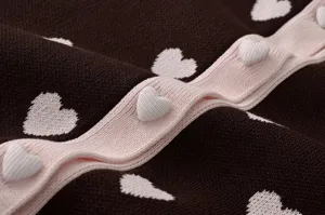 Vue rapprochée du pull en tricot montrant les jolis boutons cœur et le jacquard.