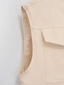 Beige vest detail view showcasing sleeveless cut and flap pocket, fine stitching craftsmanship.