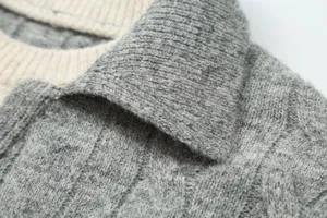Detailed view of women's cable knit fake two piece sweater featuring contrast lapel collar.