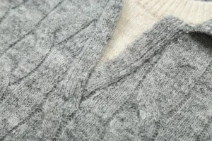 Close-up detail of women's grey cable knit sweater collar with contrast layered design.