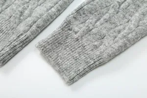 Close-up detail of grey cable knit sweater sleeve, soft texture rib cuff women wear.