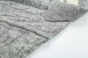 Grey cable knit sweater detail showing ribbed lapel and textured knit pattern close up.