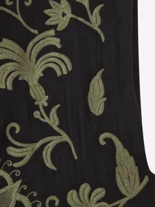 Vista detallada de alta calidad de tela negra con elegante bordado botánico verde oliva.
