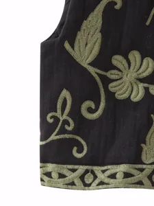 Primer plano de un chaleco negro elegante con detalles de bordado floral verde.