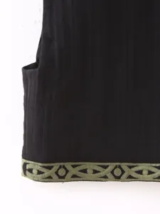 Detalle de chaleco sin mangas negro para mujer con dobladillo bordado verde y patrón geométrico.