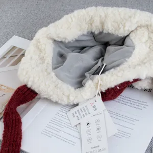 Close-up of plush red knitted ushanka hat with soft white fleece lining and warm ear flaps.