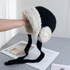 Black knitted ushanka hat with warm fluffy fleece lining, earflaps and long braided straps for winter.