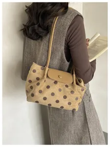 Dettaglio della elegante borsa a spalla con pois e patta in un contesto quotidiano.