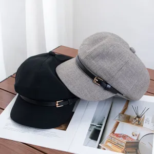 Vue détaillée de casquettes gavroche rétro en laine noire et grise avec boucle élégante.