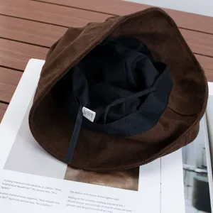 Detailed view of the brown suede bucket hat, showing texture, inner lining and label.