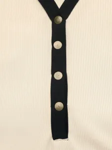 Dettaglio body a coste con scollo a V, bordo nero a contrasto e bottoni automatici metallici.