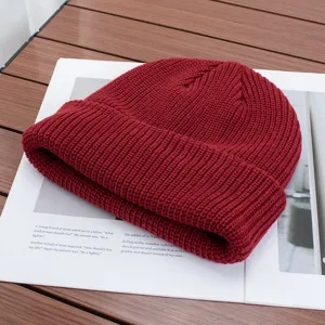 Detailed view of a solid color knit beanie hat in burgundy, warm and stylish for autumn and winter.