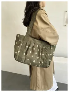 Dettaglio borsa a spalla verde a pois con eleganti pieghe arricciate e tasche laterali.