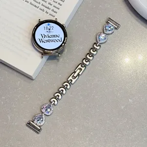 Détail de bracelet de montre connectée en métal avec charms cœur en cristal et style luxe.
