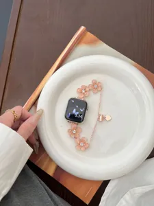 Detailansicht eines roségoldenen Blumen-Uhrenarmbands mit funkelnden Strasssteinen und Anhängern.