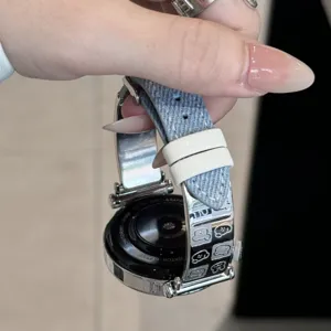 Detailed view of a metal and denim leather smartwatch strap with cute cartoon character engravings.
