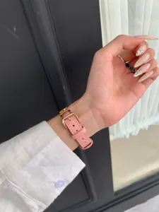 Detailed view of the pink litchi grain leather watch strap with rose gold pin buckle.