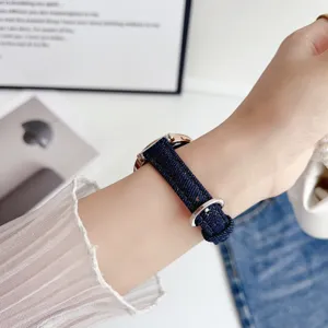 Detailed close-up of a stylish dark blue denim watch strap worn elegantly on a slim wrist.