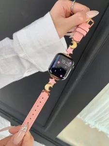 Pink leather Apple Watch strap detail with cute star and moon metal charms and rose gold hardware.