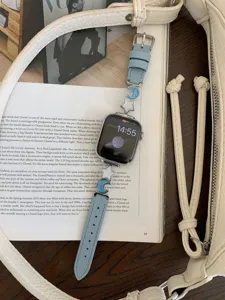 Detailed close-up view of light blue leather apple watch strap featuring cute star and moon charms.