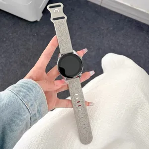 Primo piano del cinturino in silicone grigio con elegante motivo floreale di rose inciso.