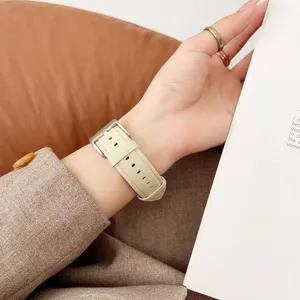 Gros plan sur le bracelet de montre en cuir beige véritable, boucle métallique élégante.
