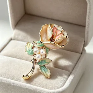 Gros plan de la broche fleur rose émaillée vintage dorée avec des perles dans écrin.