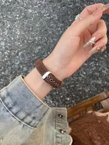 Close up detail of brown canvas watch strap worn on wrist, metal buckle texture view.