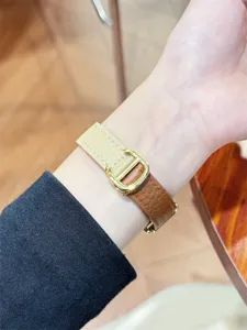 Detailaufnahme des eleganten Lederarmbands am Handgelenk mit zweifarbigem Design.