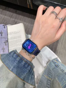 Détail de bracelet de montre en denim brodé avec motifs d'étoiles et de cœurs.