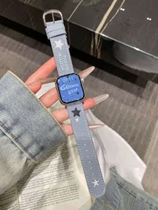 Détail de bracelet de montre en jean bleu avec étoiles brodées et design de lettrage.