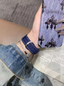 Vue détaillée du bracelet de montre en denim, texture de tissu de qualité et boucle métal.
