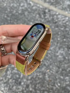 Canvas smartwatch strap detail, green fabric and brown leather design, durable metal buckle.