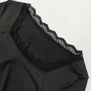 Close-up detail of women's black long sleeve top featuring elegant square neckline and lace trim.
