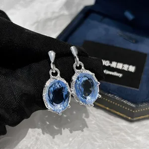 Primo piano dettagliato di squisiti orecchini pendenti in cristallo blu con dettagli in zircone.