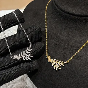 Detail view of zircon encrusted wheat ear pendant necklace in gold and silver tones.