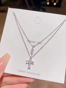 Double layered cross pendant necklace detail shot, silver chain with sparkling zircon stones.
