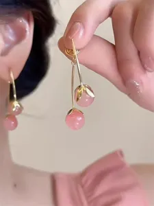 Nahaufnahme von rosa Kirsch-Ohrhängern mit transluzenten Perlen und goldenen Blättern.
