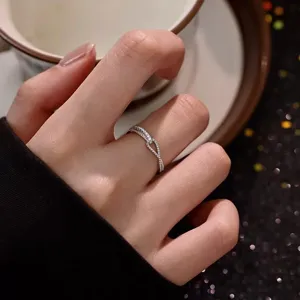 Nahaufnahme eines silbernen Zirkon-Kreuzrings am Finger, elegantes und glänzendes Design.