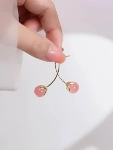 Nahaufnahme im Detail der süßen rosa Kirsch-Ohrringe, glänzender Goldstiel mit schöner Perle.