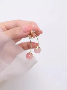 Nahaufnahme der süßen rosa Kirsch-Ohrhänger mit eleganten Goldstielen und glänzenden Perlen.