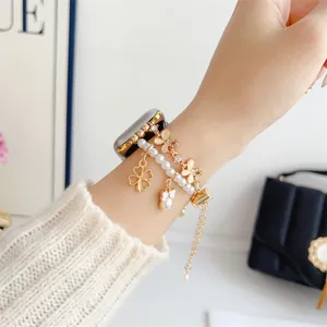 Vue détaillée d'un élégant bracelet de montre en métal décoré de perles, trèfles et papillons.