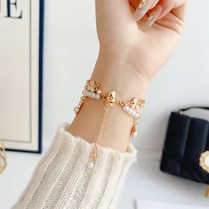 Gros plan detail du bracelet montre metal de luxe avec perles et amulettes trèfle