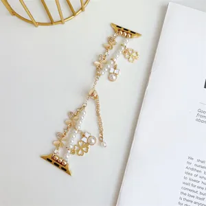 Vue détaillée du bracelet de montre en métal doré avec perles et charmants trèfles.