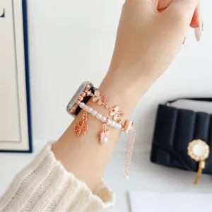 Vue détaillée du bracelet de montre Apple en métal or rose avec perles, trèfle et nœud.